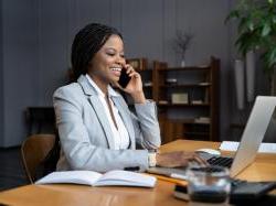 black business woman typing on a computer and talking on phone.