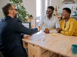 black business owners sitting at a table shaking hands with banker